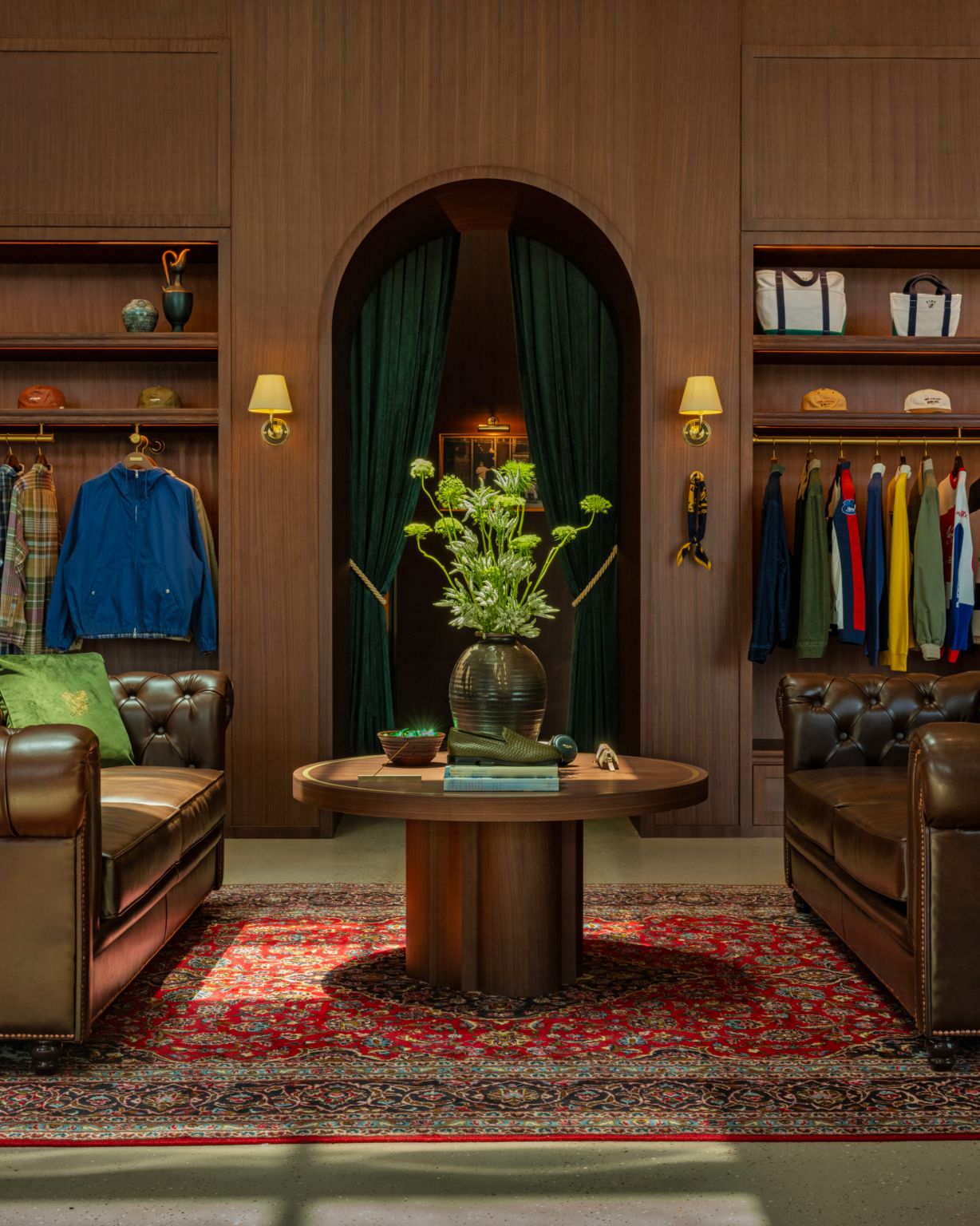 Lounge setting framed by apparel displays, green curtains and floral styling