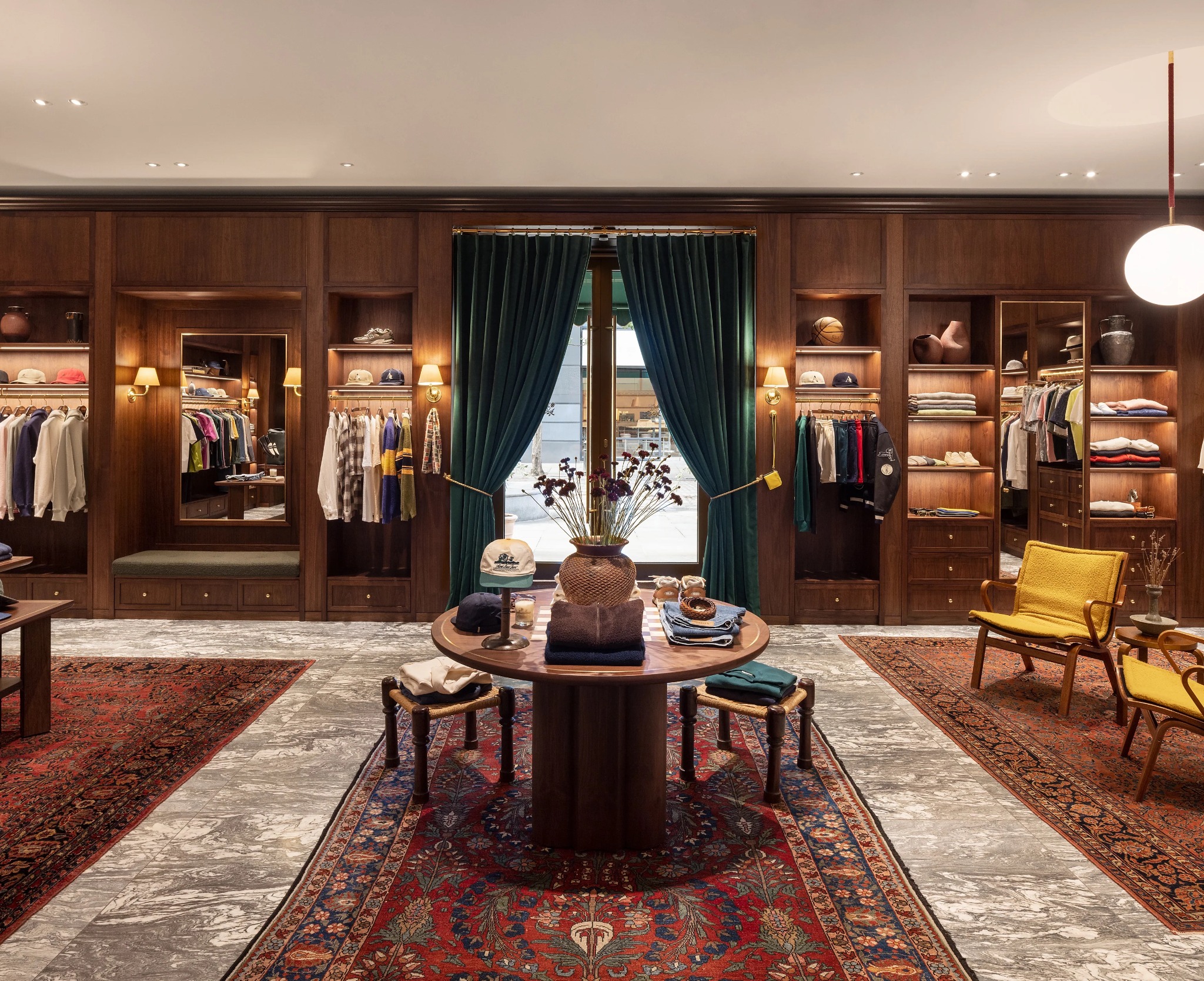 A symmetrical view of the London flagship floor with walnut fixtures, Persian rugs and central product table